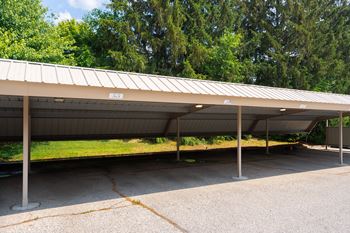 a covered parking lot with trees in the background at Bristol Square & Golden Gate Apartments in Wixom, MI